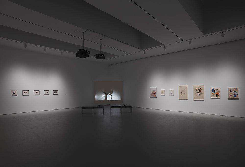 Photographs by Alvin Baltrop (left) and prints by Glenn Ligon (right) flank Kara Walker's video, "8 Possible Beginnings or: The Creation of African-America, a Moving Picture"<br>(Courtesy of David Zwirner)